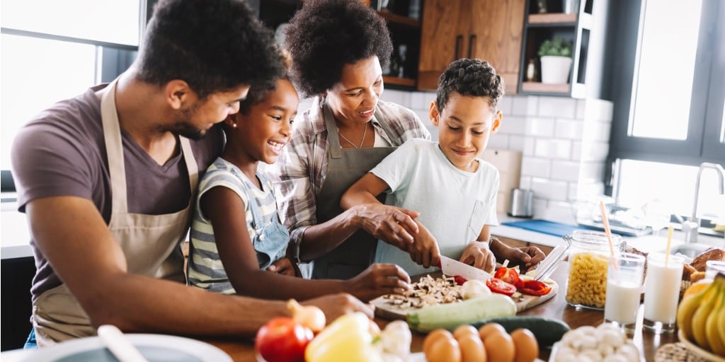 Happy African American family preparing healthy food together in kitchen stock photo