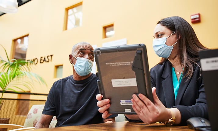 doctor holding tablet looking at patient 