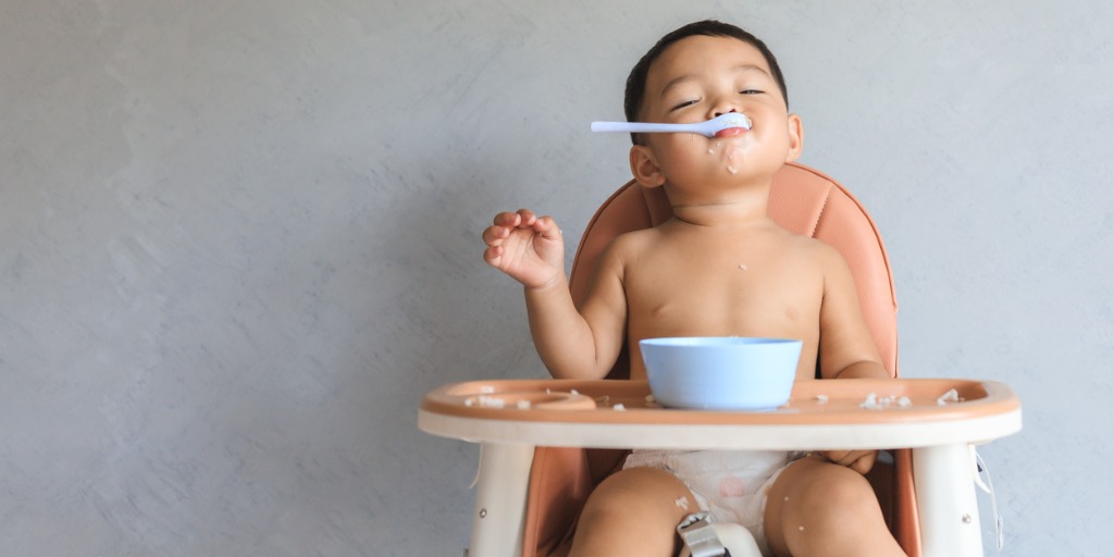 baby-boy-eating-food-by-himself-in-highchair