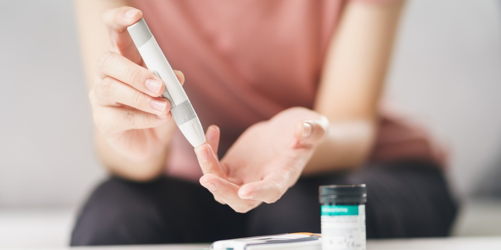 woman using lancet on finger for checking blood sugar level by Glucose meter