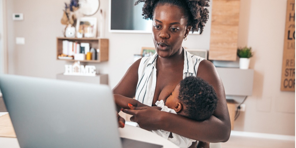 mom working on computer while breastfeeding child