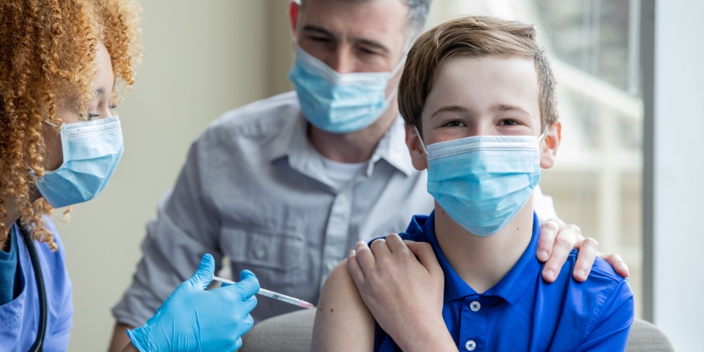 child getting vaccinated next to his dad