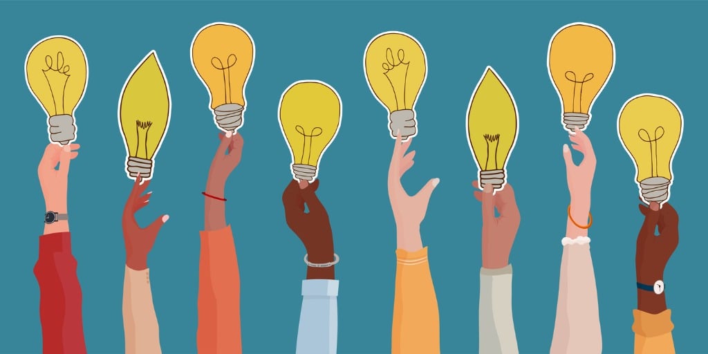 Raised arms of diverse and multi-ethnic business people holding a light bulb 