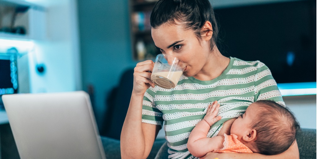 mom sipping coffee while breastfeeding baby